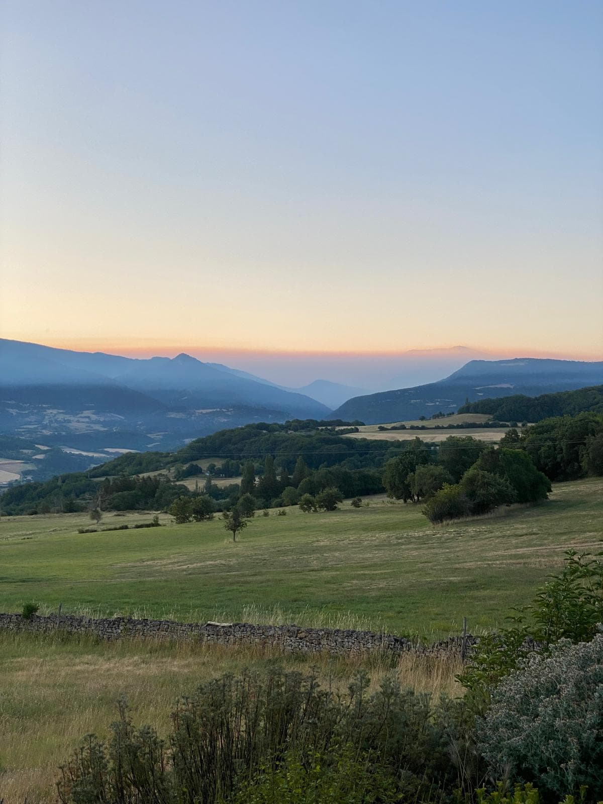 Le vallon de Bourdeaux au lever du jour, brume sur les montagnes et mur de pierres sèches au premier plan