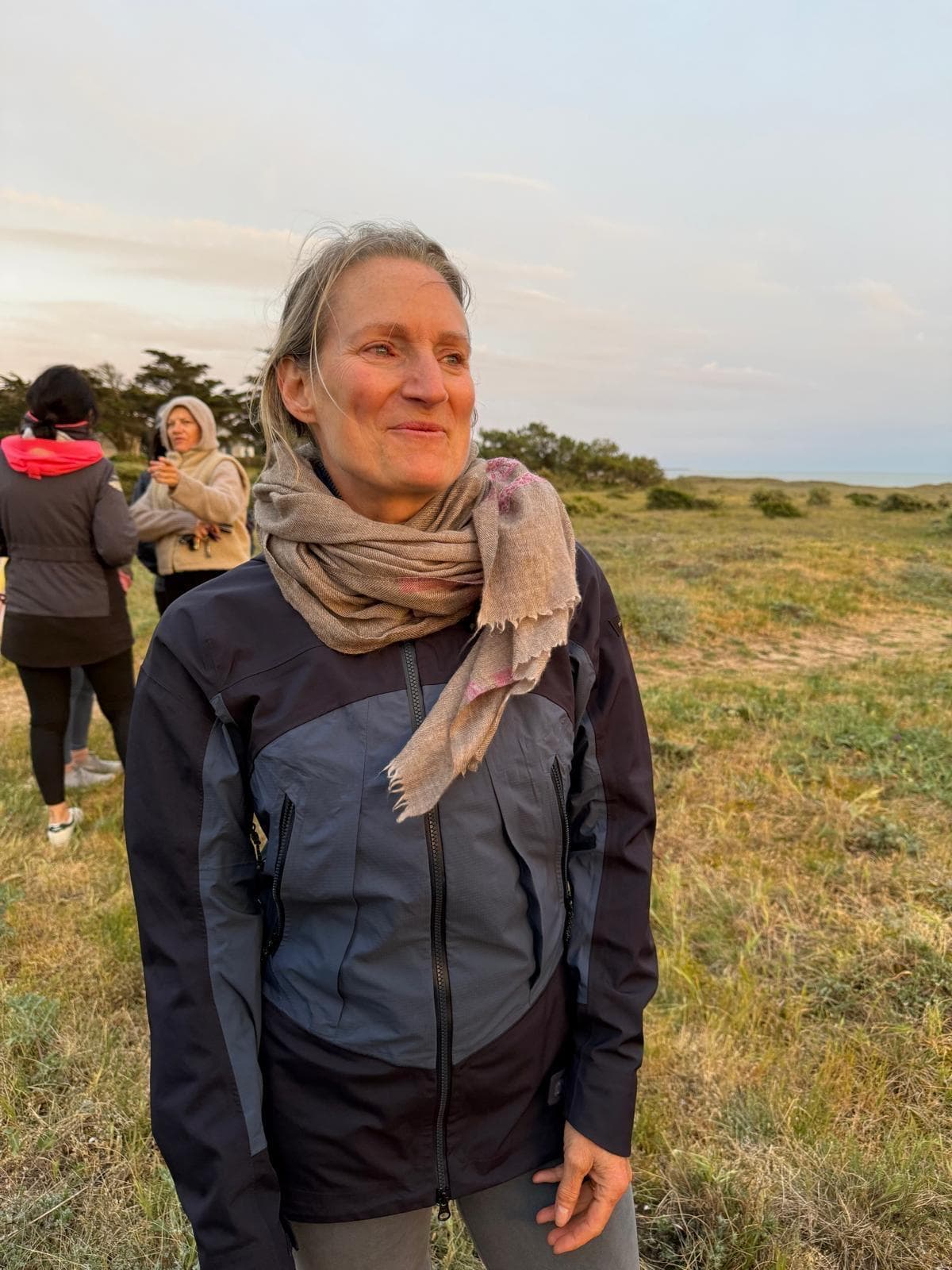 Laurence debout dans les dunes à la fin du jour, à contre-jour