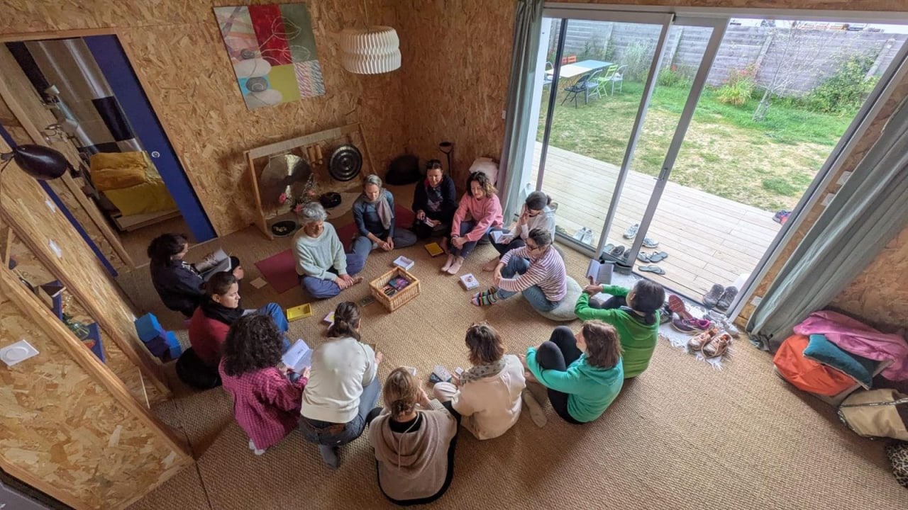 Le groupe assis en cercle dans la salle de pratique ouverte sur le jardin