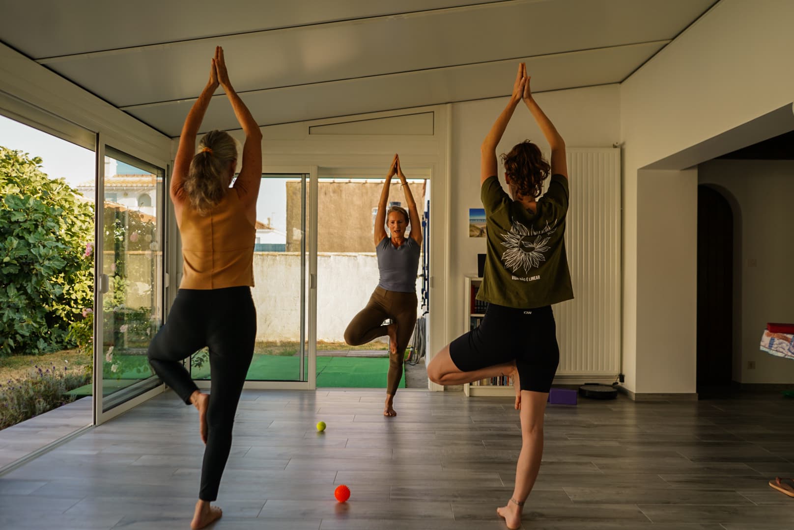 Trois élèves en posture de l'arbre, bras levés au-dessus de la tête