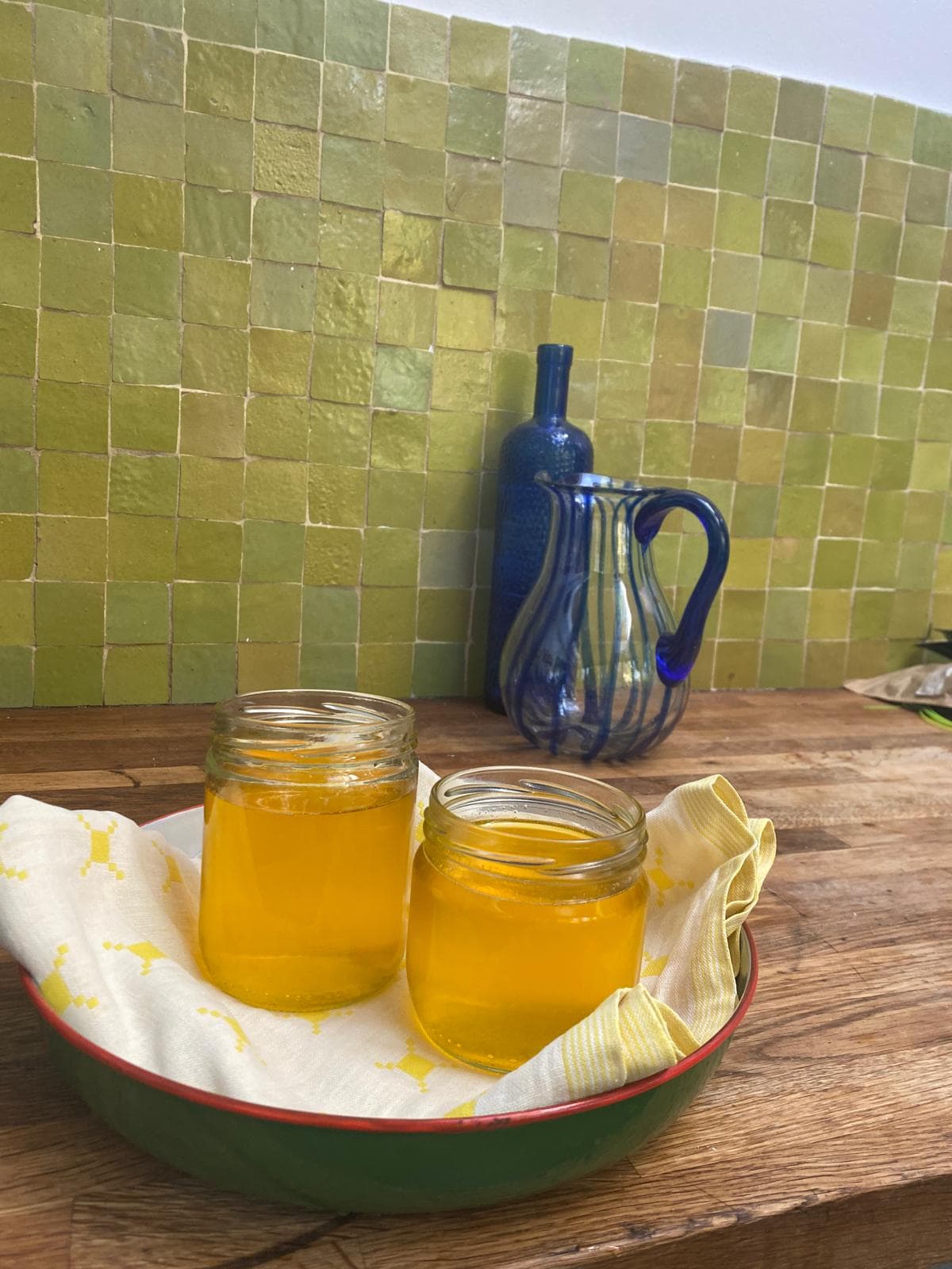 Les deux bocaux de ghee posés sur un torchon dans un plat émaillé vert