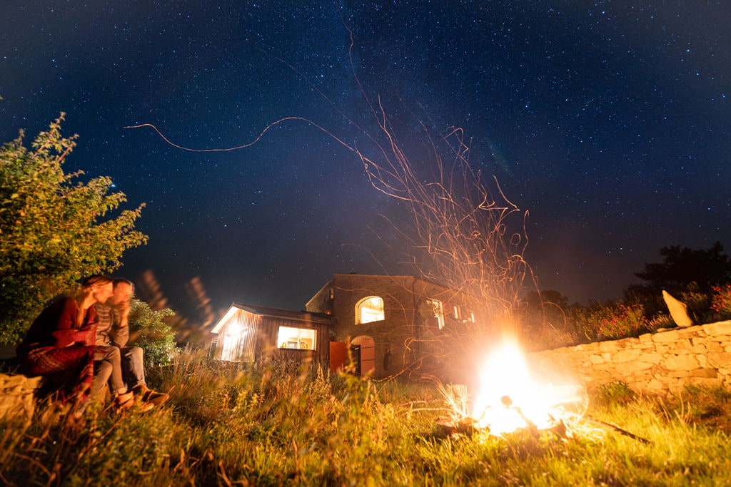 Le gîte sous les étoiles, éclairé par un feu dans le jardin