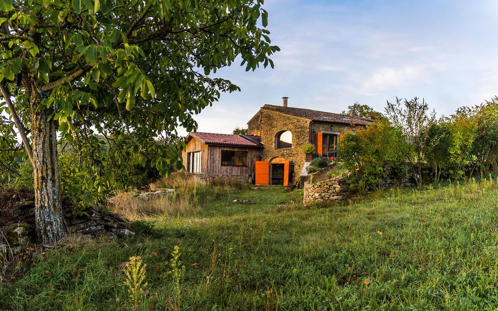 La façade de pierre du gîte, entourée de verdure